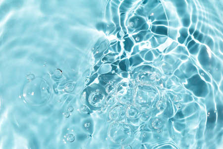 Sun glare, big bubbles on the water. Light blue textured background. Close-up, selective focus