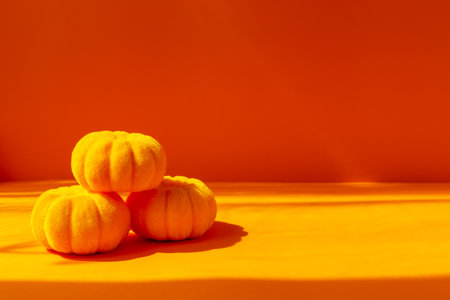 Halloween. Three pumpkins on orange background in sunlight. Front view, copy spaceの写真素材