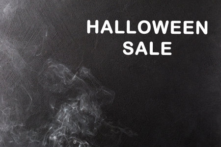 White smoke on the left on a black background rises up. On it is the inscription Halloween Sale in white lettersの写真素材