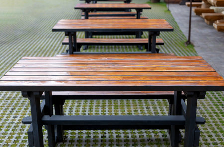 Many new wooden tables with benches are lined up outsideの写真素材