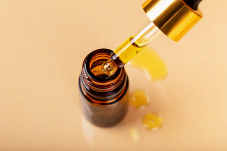 Laboratory studies. Dropper with yellow liquid was taken out of glass cosmetic amber bottle. Pipette with solution, essence, serum, emulsion. Natural organic cosmeticsの写真素材