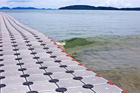 Close-up view of floating pier extending into calm sea with distant islands and cloudy sky in backgroundの写真素材