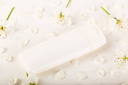 Mockup. Minimalist white skincare product laid amidst delicate cherry blossoms, showcasing serene and pure aesthetic ideal for beauty and skincare themes. Natural organic cosmeticsの写真素材