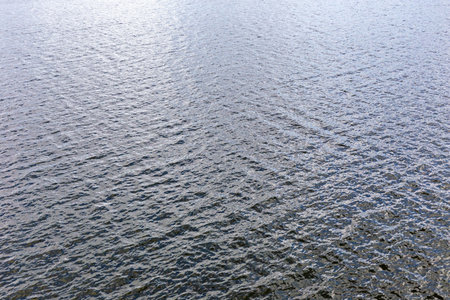 Rippling water surface showcases serene movement, sparkling reflections, and captivating texture....