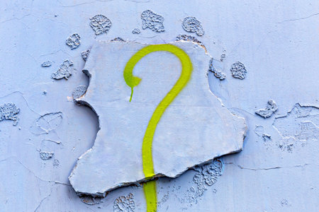 Graffiti question mark painted on cracked blue wall background. Abstract graffiti on wall with artistic creative style. Concept of graffiti as urban expressive art on aged textured wall surfaceの写真素材
