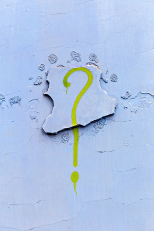 Green graffiti question mark drawn on cracked blue wall texture. Graffiti painted vertically on textured urban wall surface. Concept of graffiti as artistic creative design on wall backgroundの写真素材