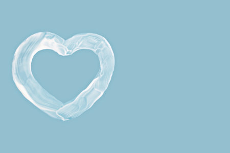 Cream heart shape on blue background with copy space, cream symbol evokes skincare, love and...