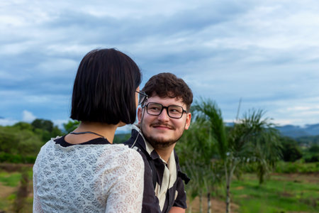 Man and woman at sunset in mountains. Young couple sharing joyful moment outdoors, surrounded by...