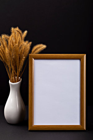 Halloween. Mockup. Empty wooden frame stands against dark backdrop, near vase of dried grass, creating perfect setting for Halloween decoration inspiration and creative design possibilities. Verticalの写真素材