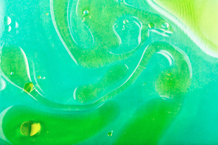 Water background with oil stains. Abstract fluid art showcases vibrant green and turquoise colors...