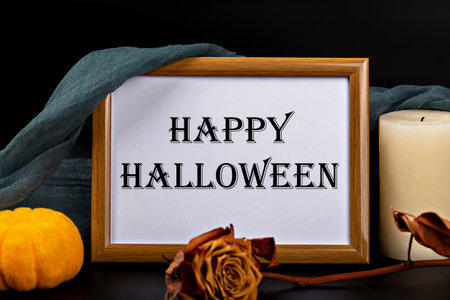 Halloween. Frame with inscription Happy Halloween is surrounded by decorative pumpkin, dried rose and candle, creating inviting ambiance perfect for Halloween decorations and seasonal displaysの写真素材