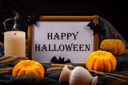 Halloween. Frame with inscription Happy Halloween on black netting surrounded by decorative pumpkins, extinguished candle with smoke and black bats, creating festive atmosphereの写真素材