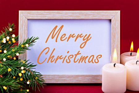 Merry Christmas. Festive holiday decoration showcases wooden frame displaying cheerful message, surrounded by greenery and lit candles, creating warm and inviting atmosphere for holiday seasonの写真素材