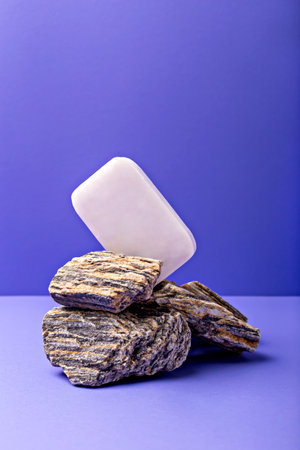 Lavender soap. Beauty and health. Minimalist composition showcases soap bar elegantly balanced on stack of textured stones, set against vibrant purple backdrop, creating harmonious aestheticの写真素材