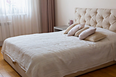 Bedroom interior. Cozy bedroom featuring elegant headboard, soft bedding and decorative pillows, creating serene atmosphere with natural light filtering through sheer curtains enhancing tranquil spaceの写真素材