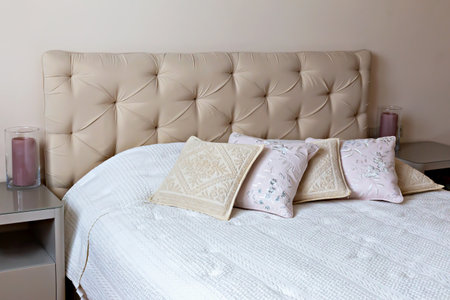 Bedroom interior. Elegant bedroom featuring beige headboard adorned with decorative pillows, complemented by soft white bedspread, creating serene and inviting atmosphere for relaxation and comfortの写真素材