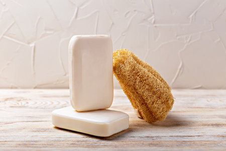 Health and hygiene. Natural soap bars are placed on rustic wooden surface alongside loofah sponge, highlighting essence of organic skincare and connection between nature and personal care routinesの写真素材