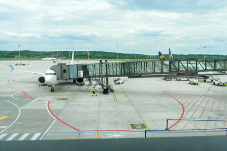 Ivan Paul II Airport, Krakow, Poland - May 07, 2025: Airplane parked at airport terminal gate with jet bridge, ground crew preparing for boarding, showcasing travel and aviation industry dynamicsのeditorial素材