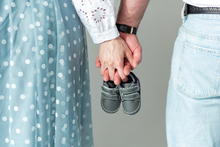 Husband and pregnant woman holding baby shoes in their hands, close-up. Motherhood, family, birth of a childの写真素材