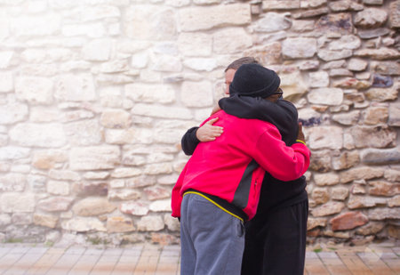 Two men, an African-American and a European, embrace when meeting against a stone wall. The concept of friendship and greeting.の写真素材