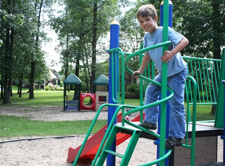 Boy in blue jeans climbing a round pole in  playground