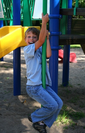 Boy in blue jeans sliding down a pole in a parkの写真素材