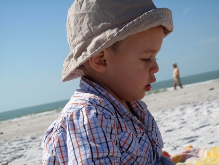  Child with cap playing  in sand                               の写真素材