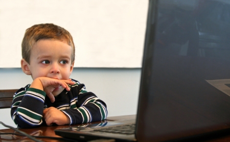 Toddler with striped shirt looking at computerの写真素材