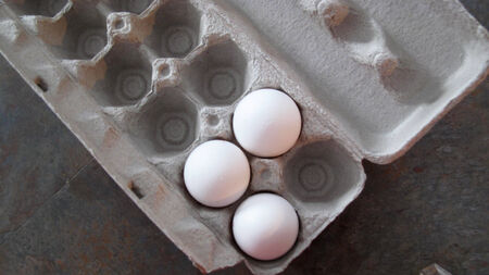    Three white fresh eggs in a crate                             