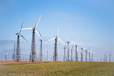 View of many wind turbines on blue sky background.