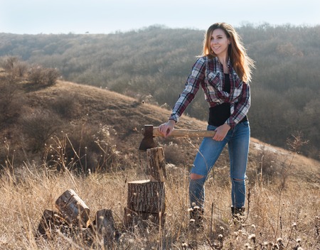 Beautiful sexy smiling woman chopping wood with axeの写真素材