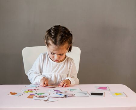 Cute little girl in white shirt playing puzzle.の写真素材