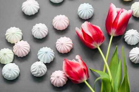 meringues in pastel colors with three red tulips on grey background.の写真素材