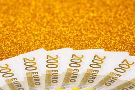 200 euro bills on golden sparkling background. A lot of money, luxury