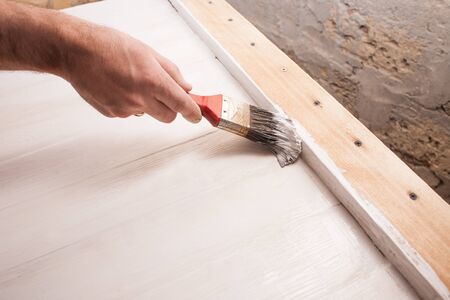 Mans hand painting wooden table with brushの写真素材