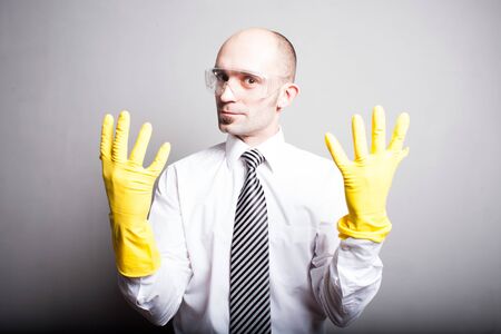 Man in white shirt in yellow latex gloves and plastic glassesの写真素材