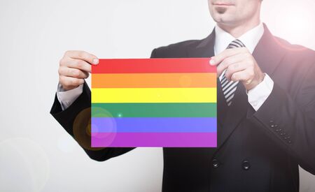 Man in business suit holding LGBT flag in hands.の写真素材