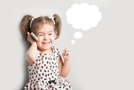 Hppy Little girl talking on phone. Blue speech bubble at the top of the photo for your text