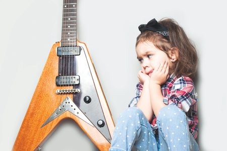 Beautiful artistic little girl playing guitar on grey background, Place for your textの写真素材