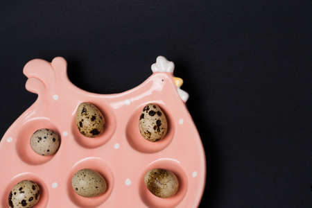 Ceramic chicken placement for eggs with Quail eggs on dark background. Easter celebration concept....