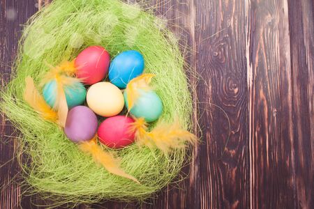Easter eggs in nest on a wooden background. Colorful