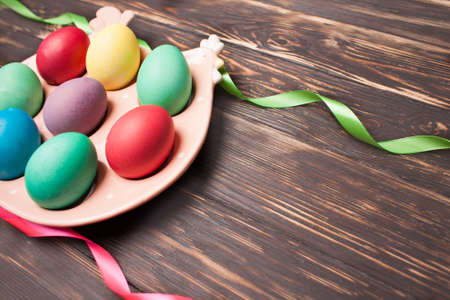 Colorful easter eggs on Ceramic chicken placement for eggs on wooden background. Easter celebration concept. close upの写真素材