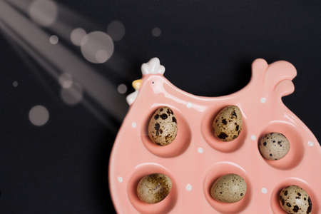 Ceramic chicken placement for eggs with Quail eggs on dark background. Easter celebration conceptの写真素材