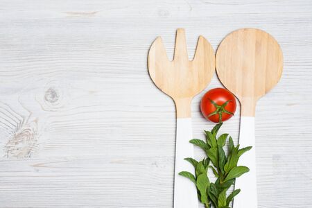 tomato and mint leaves with wooden cutlery on white wooden backgroundの写真素材