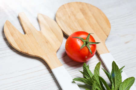 tomato with wooden cutlery on white wooden background, close upの写真素材