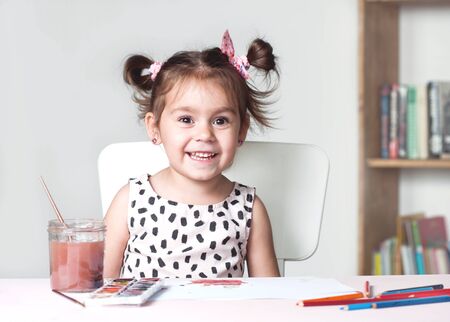 Pretty and cute little girl painting picture with watercolor in studio. Concept of education process. Scandinavian interior.の写真素材