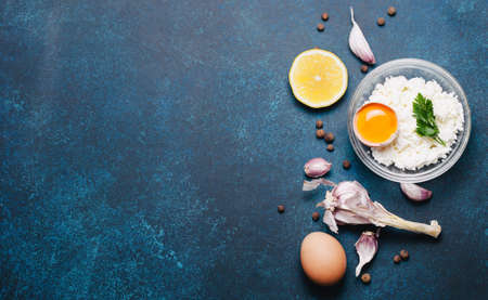Food organic ingredients: cottage cheese, egg, garlic and parsley on dark background. Top view, flat lay.の写真素材