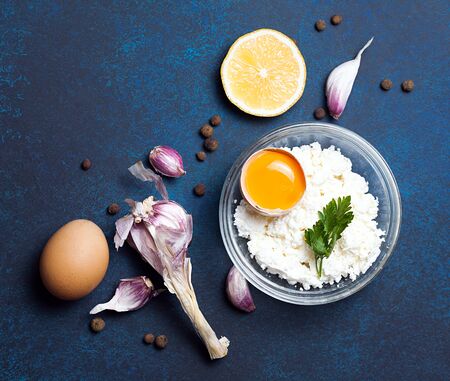 Food organic ingredients: cottage cheese, egg, garlic and parsley on dark background. Top view, flat lay.の写真素材
