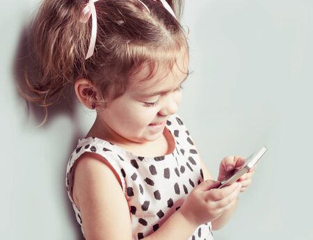 Cute little girl holds teleprone and notes to empty space for your text. Close up portraitの写真素材