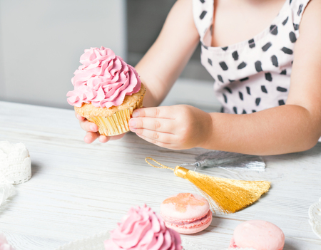 Cute little girl holding birthday cupcakes in kitchen. Festive and holiday conceptの写真素材